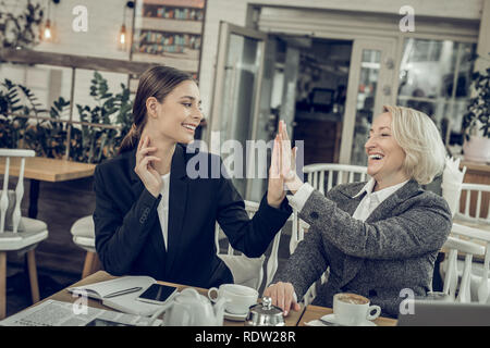 Mère rire moderne haute donnant cinq à sa fille Banque D'Images