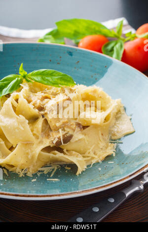 Les pâtes italiennes les pappardelle avec un mélange de champignons sauvages, sauce au fromage crémeux et le parmesan. Servi avec du basilic. Close-up shot. Banque D'Images