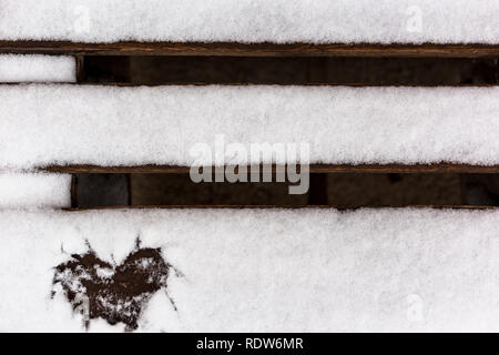 Coeur dessiné dans la neige sur un banc en bois, vue du dessus. Carte de voeux de la Saint-Valentin avec place pour le texte. Banque D'Images