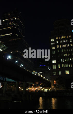 Vue de nuit sur un train qui passait un pont au-dessus de la rivière Thames, à Canary Wharf à Londres, Royaume-Uni Banque D'Images