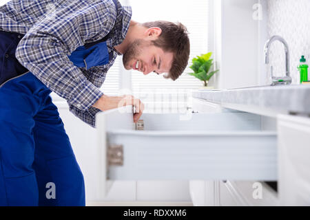 Close-up of a male Carpenter Installation porte de tiroir dans la cuisine Banque D'Images