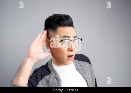 Portrait de jeune homme qui surprend une conversation sur fond blanc Banque D'Images