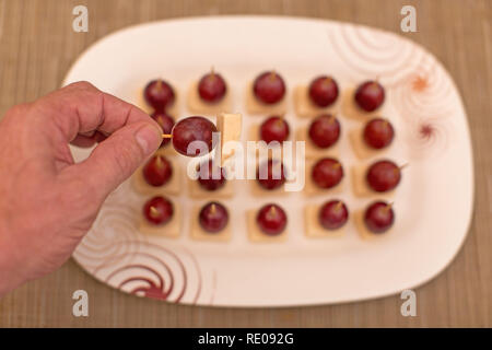 Les raisins et le fromage comme cure-dent et stick snack apéritif avec un mans cueillette à la main un délicieux en-cas Banque D'Images