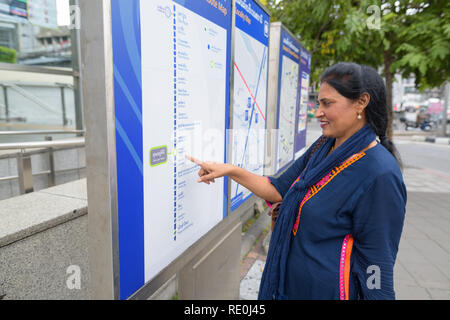 Belle mature femme indienne à la carte train à l'extérieur Banque D'Images