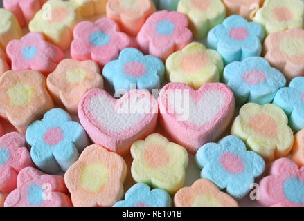 Une paire de rose et de blanc en forme d'coeur Marshmallow parmi la queue en forme de fleur Pastel Bonbons Guimauve Banque D'Images