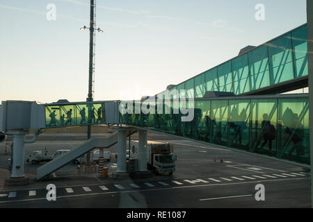 Les passagers débarquant d'un vol à l'aube, l'Aéroport International de Cape Town se sihouetted contre un ciel coloré dans le passage entre l'avion t Banque D'Images