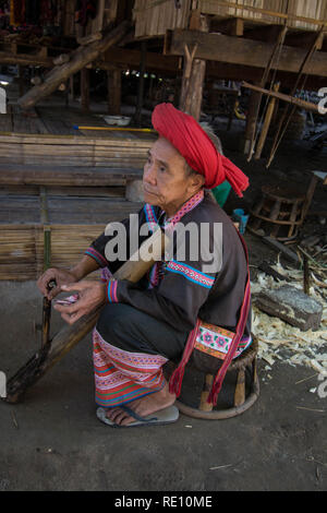 Femme asiatique assise avec turban en Hmong Thaïlande Asie chapeau de dame assis assis travail de travail robe de travail rouge sac de chapeau face à la vieille personne place tissu en bois vendre Banque D'Images