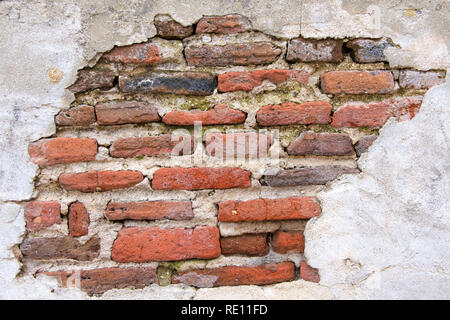 Vieux mur de briques recouvertes de béton, béton usé météo s'est effondré à l'écart de la couche sous-jacente révélant la brique. L'état de décrépitude. Banque D'Images
