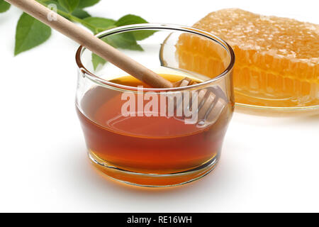 Balancier en bois dans un bol en verre de miel et de miel isolé sur fond blanc Banque D'Images