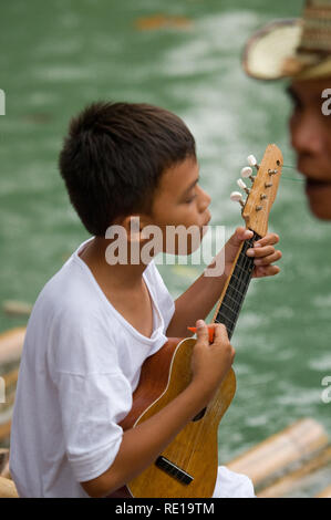 Certains enfants chantent et dansent sur les marges de la rivière Loboc quand les touristes arrivent alors qu'ils prendre un bateau. Bohol Philippines Loboc Banque D'Images