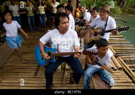 Certains enfants chantent et dansent sur les marges de la rivière Loboc quand les touristes arrivent alors qu'ils prendre un bateau. Bohol Philippines Loboc Banque D'Images