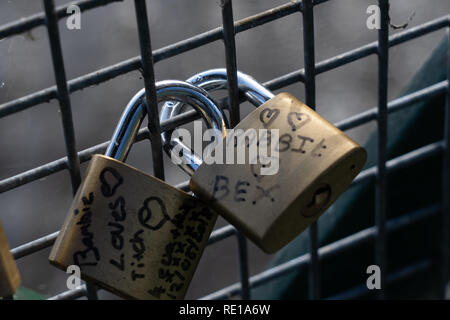 Deux cadenas verrouillés ensemble sur une clôture en métal avec des noms inscrits sur ces cadenas. Banque D'Images