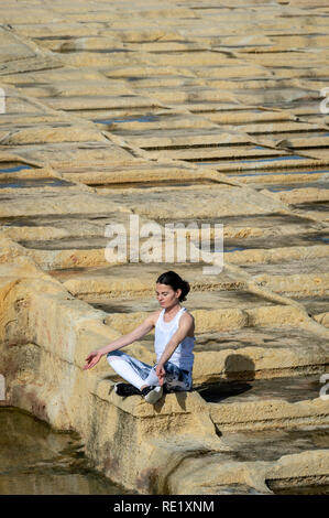 Femme méditait, assis parmi les salines de calcaire à Malte Banque D'Images