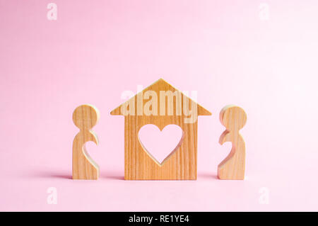 Une maison avec un cœur se tient entre une paire d'amants. Le concept de trouver un nid d'amour. Logement à prix abordable pour les jeunes familles et les couples. Prêt hypothécaire, Banque D'Images