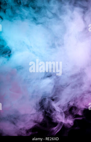 Des nuages de fumée de couleur isolées : bleu, rouge, vert, rose, à défiler sur un arrière-plan noir vertical dans l'obscurité close up. Banque D'Images