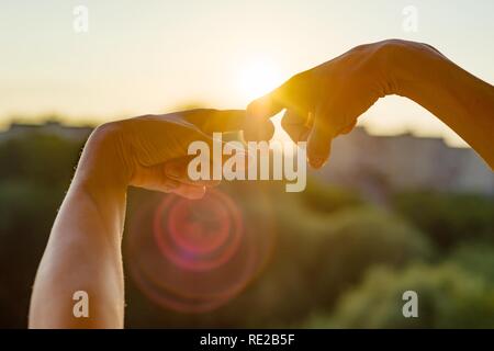 Montrer les mains geste du doigts, symbole de l'amitié et relation. Coucher de soleil en arrière-plan, silhouette ville Banque D'Images