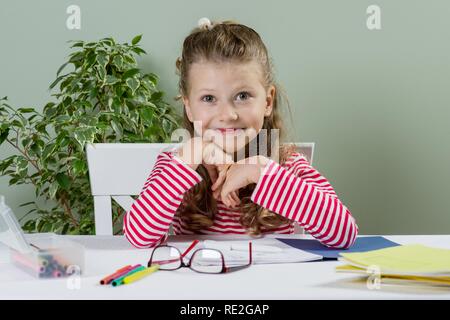 Junior lycéenne mignon avec des cheveux blonds, souriant, dans une école de dessin et ordinateur portable s'amusant à la maison à une table Banque D'Images