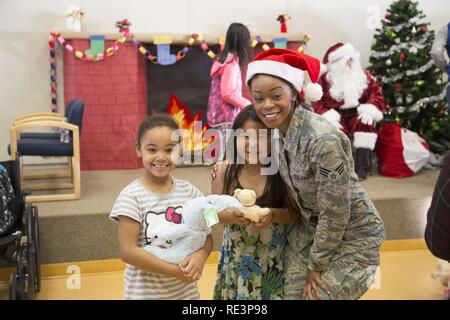 Airman Senior Denise Barnes, avec l'Air Force Reserve's 55e Escadron Port Aérien, pose pour une photo avec deux étudiants locaux au cours de l'Opération Père Noël à Togiak, 15 novembre 2016. Barnes a été l'un d'une poignée de réservistes du Travis Air Force Base, en Californie, qui participait à la formation annuelle conjointe à Base-Elmendorf Richardson et se sont portés volontaires pour participer à la Garde nationale de l'Alaska community outreach program. Maintenant dans sa 60e année, l'Opération Père Noël continue d'offrir des jouets, des fournitures scolaires et autres cadeaux aux enfants dans les villages de l'Alaska. Banque D'Images