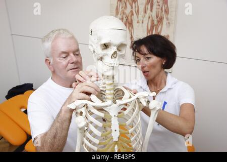 Thérapeute d'expliquer à un patient la base anatomique pour la thérapie physique, basé sur un squelette, de physiothérapie dans Banque D'Images