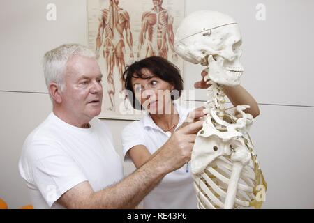 Thérapeute d'expliquer à un patient la base anatomique pour la thérapie physique, basé sur un squelette, de physiothérapie dans Banque D'Images