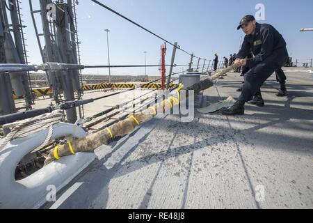 SALALAH, Oman (nov. 13, 2016) Maître de 2e classe Kyle Purser se soulève une ligne de mouillage sur le gaillard de missiles de l'USS Roosevelt (DDG 80) au cours de l'ancre et la mer détail. Roosevelt, déployés dans le cadre du groupe aéronaval d'Eisenhower, appuie les opérations de sécurité maritime et les efforts de coopération en matière de sécurité dans le théâtre dans la 5e flotte américaine zone d'opérations. Banque D'Images