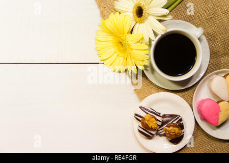 Fleurs romantique avec café et friandises sur la table Banque D'Images