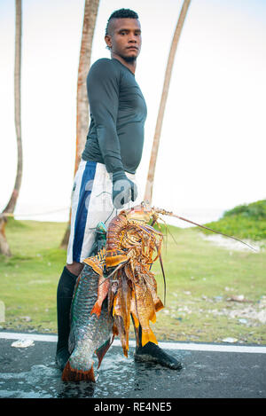 Homme latino inconnu tenant fièrement ses prises : Le homard frais et de poisson géant. Portrait de l'environnement, usage éditorial. San Andrés, Colombie. Oct 2018 Banque D'Images