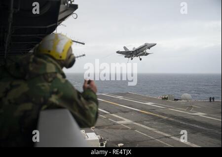 Océan Atlantique (nov. 29, 2016) Un marin montres un F/A-18 Hornet, attribué aux Romains de Strike Fighter Squadron (VFA) 106, voler au-dessus du pont d'envol du porte-avions USS George Washington (CVN 73) pendant les opérations de vol. George Washington, homported à Norfolk, est en cours la réalisation des qualifications de l'opérateur dans l'océan Atlantique. Banque D'Images