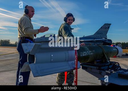 Le sergent-chef de l'US Air Force. Roger McKay, chef d'équipe, à gauche, et l'Aviateur Senior Sydney Byrd, chargeur d'armes, tous deux assignés à la 169e Escadron de maintenance des aéronefs, de se préparer à passer une bombe sur la voie de circulation à la base de la Garde nationale mixte Guess, Caroline du Sud, du 22 novembre 2016. La Caroline du Sud Air National Guard's 169e Escadre de chasse est la seule e escadre de chasse dans l'Air National Guard, qui est assigné à une base autonome, permettant la mesure de stocker, de construire, de la charge, et d'abandon de tactiques en direct de la station d'accueil. Banque D'Images