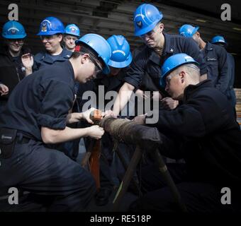 NEWPORT NEWS, Virginie (nov. 8, 2018) --électricien (nucléaire) 2e classe Zach Lewis, gauche, de Cambridge, de l'Ohio, l'Aviation 3e classe Ordnanceman Eric Heavener, centre, de Tecumseh, Michigan, et l'Aviation maître de Manœuvre (manutention) 3e classe Addison Williams, de Fort Espagnol, Alabama, tous affectés à l'USS Gerald R. Ford (CVN 78), une rupture du tuyau de raccordement au cours du contrôle des avaries qui a eu lieu dans le hangar du navire. Ford est actuellement en post-shakedown la disponibilité de Huntington Ingalls Industries-Newport News Shipbuilding. Banque D'Images