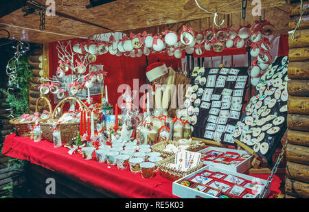 Brasov, Roumanie - 2 décembre 2018 : Vendeur wearing Santa hat attend les clients à visiter son stand rouge affichant une décoration traditionnelle faite maison Banque D'Images