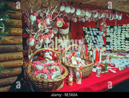 Brasov, Roumanie - 2 décembre 2018 : Vendeur wearing Santa hat attend les clients à visiter son stand rouge affichant une décoration traditionnelle faite maison Banque D'Images