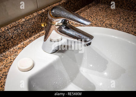 Lavabo moderne avec le robinet dans la salle de bains de la chambre d'hôtel. Banque D'Images