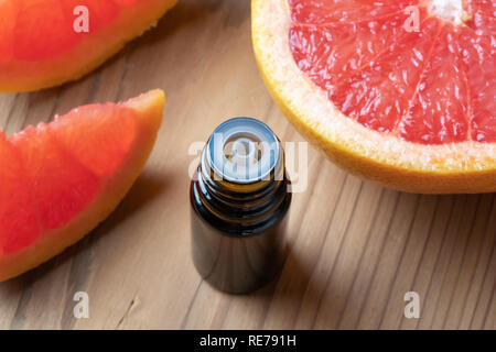 Une bouteille d'huile essentielle d'agrumes avec des pamplemousses frais Banque D'Images