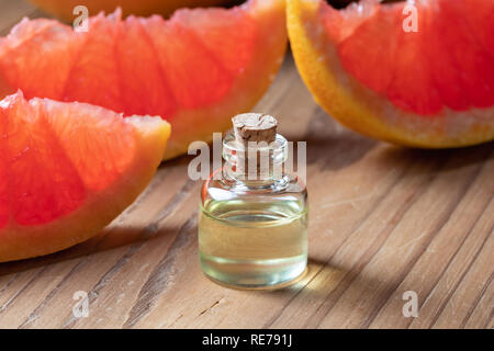 Une bouteille d'huile essentielle d'agrumes avec des pamplemousses frais Banque D'Images