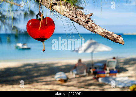 Cat Island, Bahamas. Hotel Fernandez Bay Village Resort. Les touristes se détendre sur la plage. Coeur suspendu à un arbre Banque D'Images