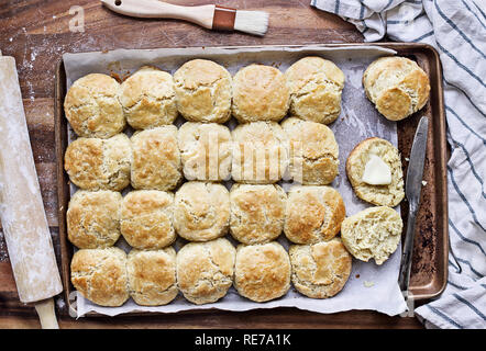 Babeurre biscuits fraîchement cuits au four du sud ou des scones à partir de zéro avec rouleau à pâtisserie et pinceau sur une plaque. Vue d'en haut. Banque D'Images