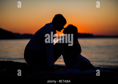 Couple assis sur fond coucher de soleil Banque D'Images