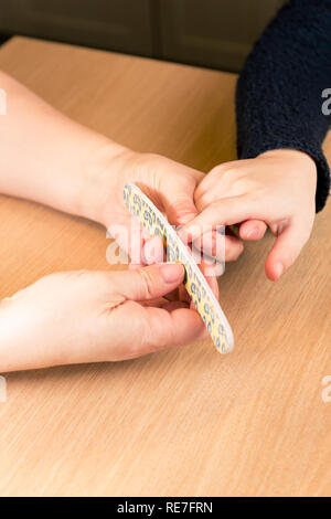 Dépôt des clous de jeune fille à la cuisine table, Close up des mains - verticale Banque D'Images