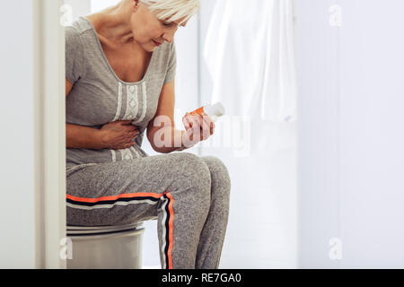 Triste belle femme d'âge mûr ayant l'intoxication alimentaire Banque D'Images