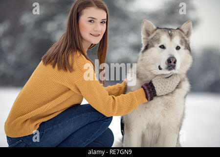 Fille est assise à côté d'un chien malamute d'Alaska et son épouse pour une promenade en hiver. Libre. Banque D'Images