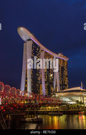 Singapour, en Asie du sud-est - 14 décembre 2018 : vue panoramique sous ciel bleu de l'Hélix Bridge et Marina Bay Sands Hotel en zone crépusculaire. Banque D'Images