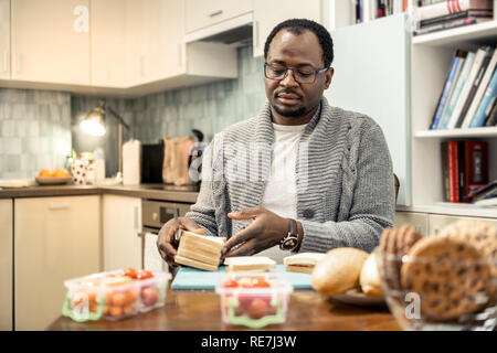 Père aimant porter des lunettes la cuisson des sandwichs pour voyage en famille Banque D'Images