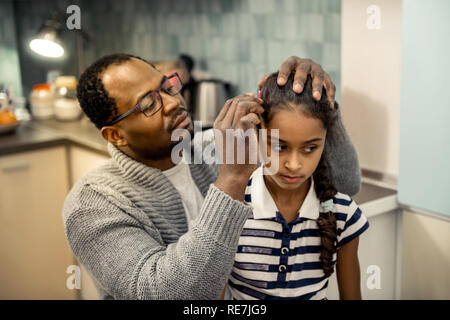 Père porter cardigan gris hairstyle fixation de sa fille Banque D'Images