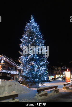 Un grand sapin de Noël en feu avec des lumières dans la nuit dans le centre de Morzine Haute Savoie Portes du Soleil France Banque D'Images