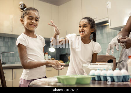 Rire joyeux frères jouant avec la farine dans la cuisine Banque D'Images