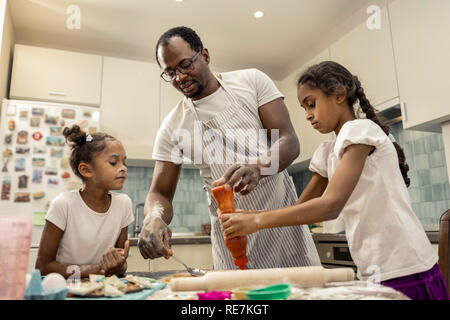 Dark-haired père et mignon filles la cuisson des pizzas pour le dîner Banque D'Images