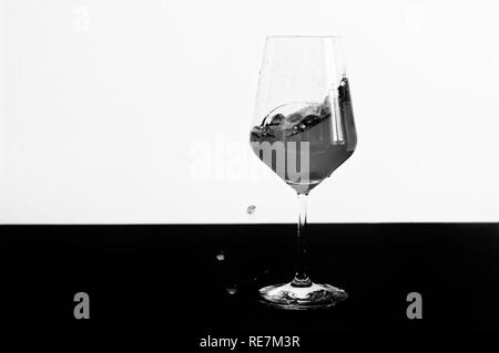 Photo en noir et blanc de vin rouge projection d'un verre Banque D'Images