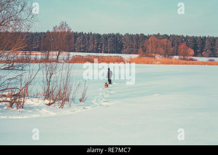 Homme marchant avec chien sur le lac gelé retour à l'appareil photo Banque D'Images