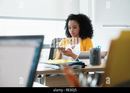 Belle jeune femme d'affaires avec téléphone cellulaire dans l'entreprise Banque D'Images
